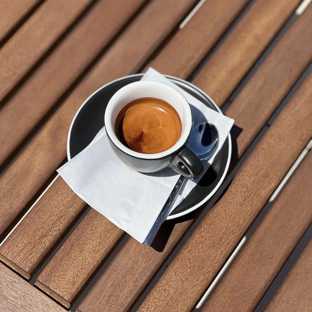 A Kofee espresso served on a sunlit wooden table